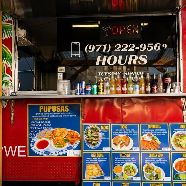 Vibrant red food truck with palm tree art, displaying menus and an "OPEN" sign.